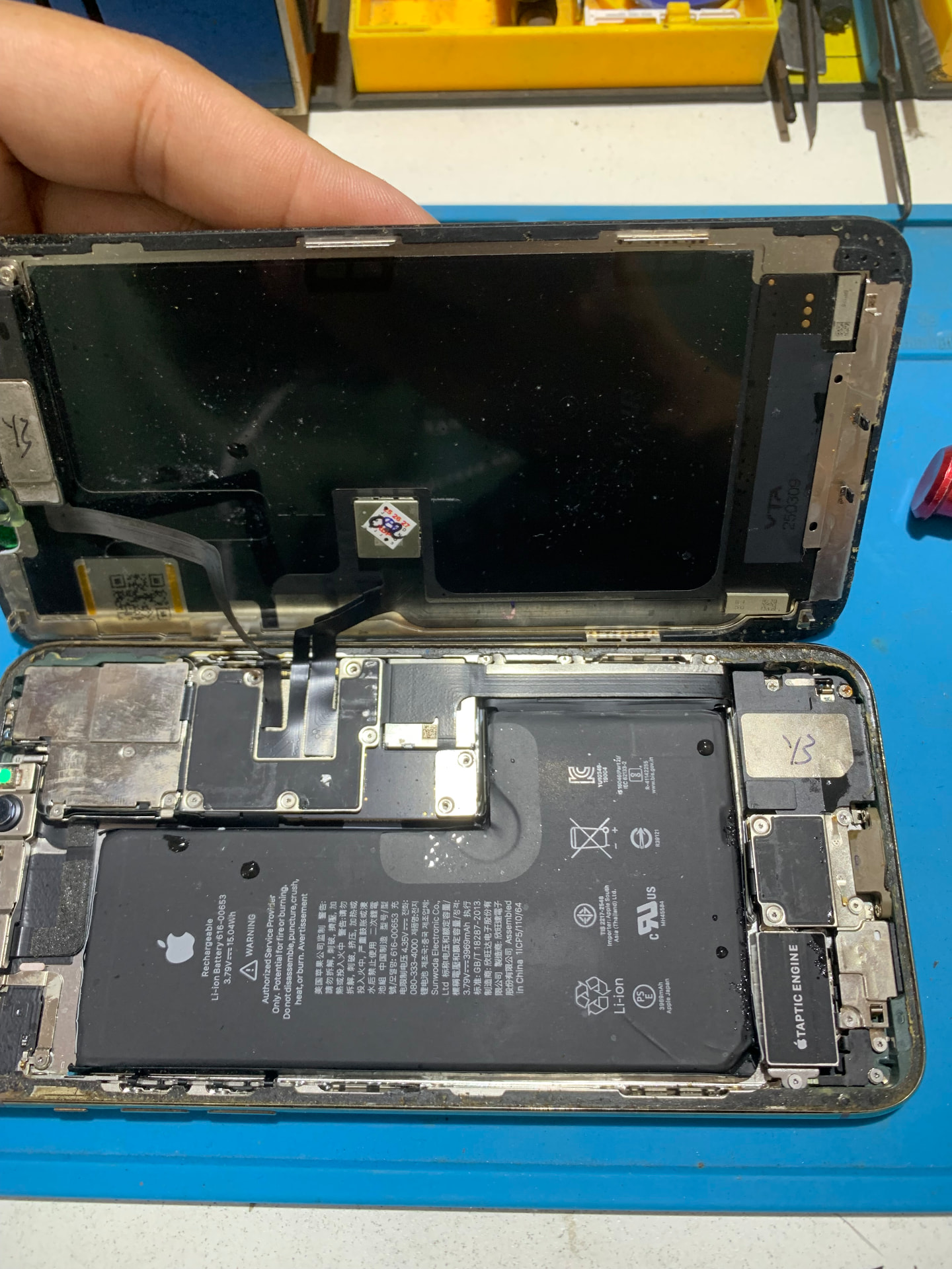 Bancada de assistência técnica com celular aberto durante manutenção
